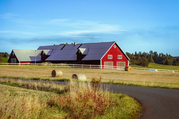 Red barn with hay bales in a field