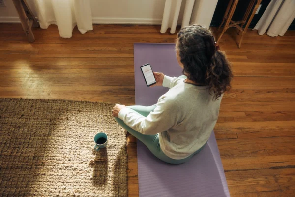 Energia Solar em Apartamento: Como Funciona 2 Woman meditating on yoga mat with phone and drink