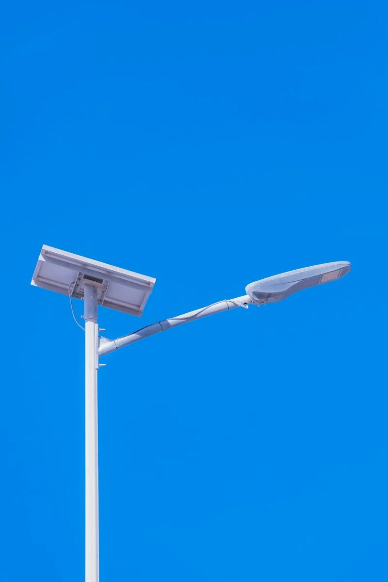 Luminária Solar de Rua: Como Funciona, Tipos e Como Especificar 1 Solar-powered streetlight against a bright blue sky