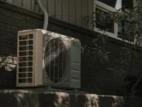 a white air conditioner sitting on top of a brick wall