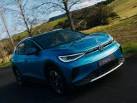 SUV elétrico Volkswagen ID.4 azul em estrada cercada por árvores