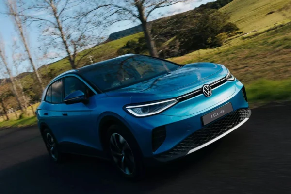 SUV elétrico Volkswagen ID.4 azul em estrada cercada por árvores